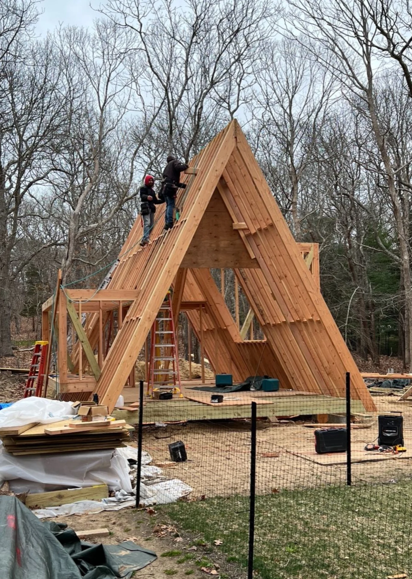 Two men working on a wooden structure in the woods.