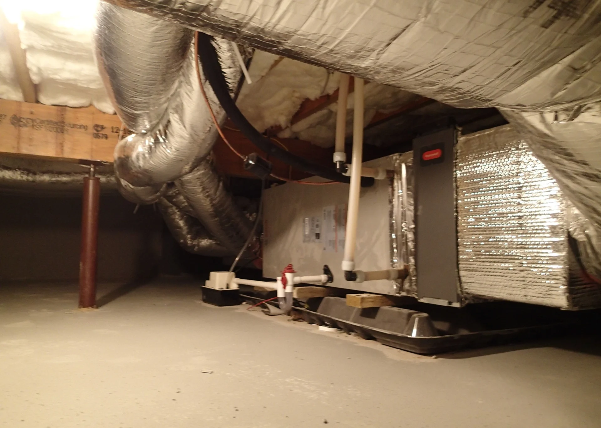 A room with duct work and air handler in it.