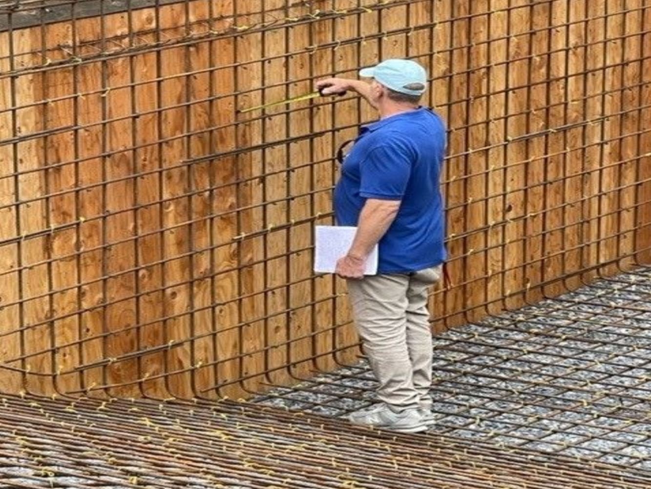 A man standing in front of a fence holding something.