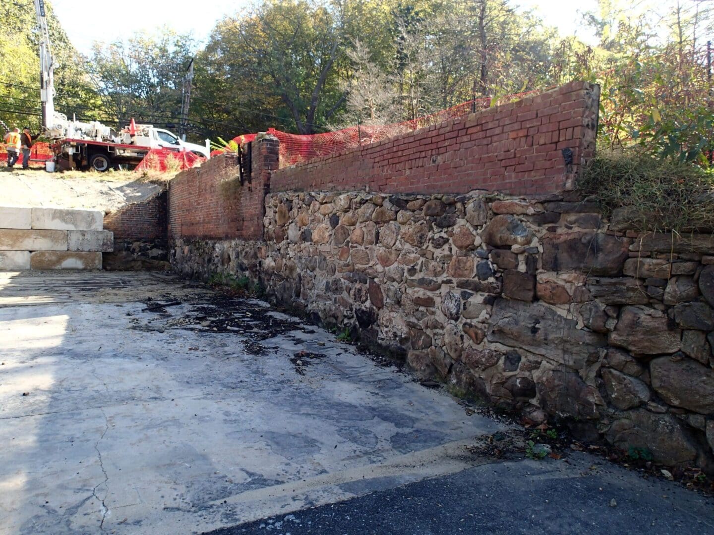 A brick wall with a concrete road in the foreground.